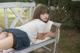 A woman laying on a bench with a book.