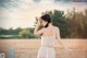 A woman in a white lingerie standing in a field.