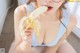 A woman in a blue tank top eating a banana.