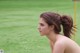 A naked woman standing in a field of green grass.