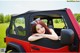 A woman leaning out the window of a red jeep.