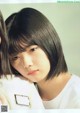 A woman with a black bob with bangs and a white shirt.