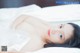 A woman laying on top of a bed in a white dress.