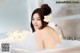 A woman sitting in a bathtub with a flower in her hair.