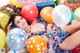 A woman laying on top of a pile of balloons.