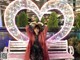 A woman sitting on a bench in front of a heart shaped sign.