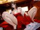 A woman in a red dress is sitting on a bed.
