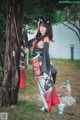 A woman in a kimono standing next to a tree.