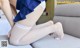 A woman in fishnet stockings is sitting on a couch.