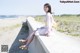 A woman sitting on a concrete wall next to the ocean.