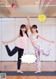 A couple of women standing on top of a yoga mat.